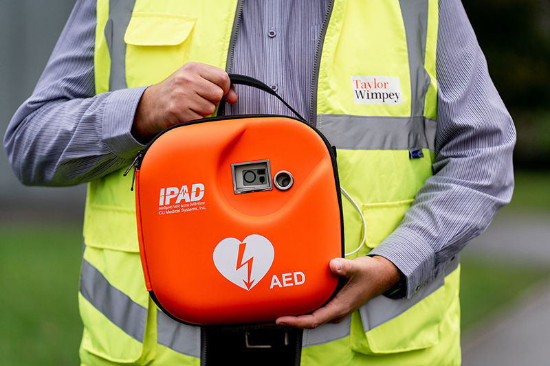 Construction worker holding defibrillator 